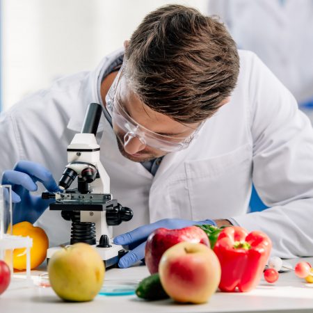 molecular nutritionist in white coat using microscope in lab